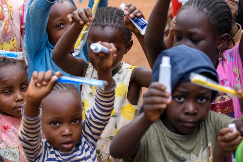 Children in Kibera holding up toothbrushes and toothpaste
