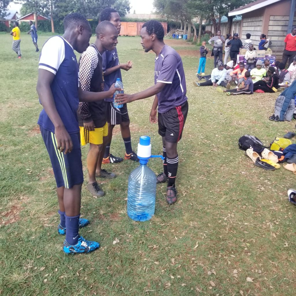 Young football players sharing clean water on the pitch